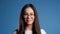 Pretty young asian girl with long hair standing on blue studio background. Cute portrait