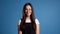 Pretty young asian girl with long hair standing on blue studio background. Cute portrait of woman