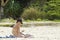 Pretty young bikini woman sun tanning sitting beach using phone