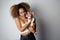 Pretty young black american african girl embracing puppy on white background. Studio portrait of white appealing female