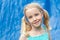 Pretty young blonde girl with pigtails making eye contact on a blurry blue background