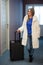 Pretty Young Blonde Woman Traveling Wearing a coat, jeans pulling a suit case