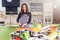 Pretty young Caucasian woman making pizza by recipe book, chopping vegetables on cutting board in her flat.