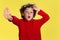 Pretty young curly boy in red wear on yellow studio background. Childhood, expression, fun.