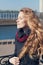 Pretty young fashion woman with long curly hair enjoying the spring sun with eyes closed near the river