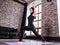 Pretty young female athlete in black sports outfit doing lunge exercise or standing in yoga low warrior pose on mat at