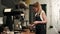 Pretty young female barista weighing coffee grains on a scale before brewing a cup of coffee