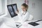 Pretty and young female doctor discusses X-ray image online with her patient via chat