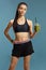 Pretty young female in sportswear holding a green smoothie