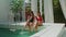 Pretty young females with drinks resting by pool