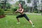 Pretty young fit woman doing stretching exercises in park. Fitness side lunges outdoors.