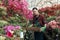 Pretty young gardener male student with trendy hairstyle holding a box with flower