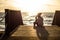 Pretty Young girl on a bridge that goes to the beach with beautiful sunset on the sea