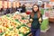 Pretty young girl choosing between ripe pear and apple at market