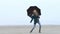 Pretty young girl dancing with umbrella and having fun on foggy beach