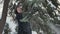 Pretty young girl shakes a snowy fir-tree