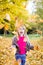 Pretty young girl with smile throws leaves in the park