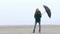 Pretty young girl twisting and spinning umbrella and having fun on foggy beach