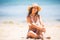 Pretty young latin pretty girl at beach. Woman sitting on sands have active time in summer playing with sand. Summertime carefree