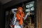 Pretty young model of a fashionable woman in a stylish knitted orange hat with a scarf in a youth trendy shiny jacket poses in the