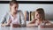 Pretty young mother and her daughter looking to each other while eating yogurt at home