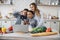 Pretty young mother and two children sons preparing salad with fresh vegetables