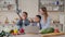 Pretty young mother and two children sons preparing salad with fresh vegetables