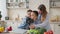 Pretty young mother and two children sons preparing salad with fresh vegetables