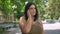 Pretty young obese woman talking on cell phone and smiling, standing on street in park, happy and cheerful