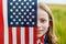 Pretty young pre-teen girl in field holding American flag.