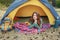 Pretty young redhead girl looking up, lying in yellow grey tent, relaxing, enjoying nature in autumn forest