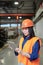 Pretty young serious female engineer in hardhat and workwear using touchpad