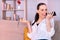 Pretty young smiling brunette woman recording an audio on the smartphone sitting on the sofa at home.