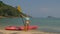 Pretty young sportswoman with sunglasses and swimsuit holds paddle posing near pink plastic canoe on sand beach at