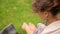 Pretty young student sitting on grass using laptop