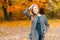 Pretty young stylish beautiful woman in trendy elegant gray coat in stylish green blouse on a walk outdoors in the park.