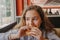 Pretty young teen girl with an appetite eating a hamburger in a cafe