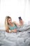 Pretty, young woman in bed, taking a selfie on her cell phone