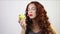 Pretty young woman bites fresh pear in white studio