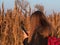 Pretty young woman in black coat with backpack smartphone on pampas grass sunset sky dry reeds Millennial long hair girl