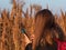 Pretty young woman in black coat with backpack smartphone on pampas grass sunset sky dry reeds Millennial long hair girl