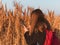 Pretty young woman in black coat with backpack smartphone on pampas grass sunset sky dry reeds Millennial long hair girl