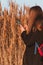 Pretty young woman in black coat with backpack smartphone on pampas grass sunset sky dry reeds Millennial long hair girl