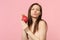 Pretty young woman blowing sending air kiss hold fresh ripe pitahaya dragon fruit isolated on pink pastel wall