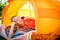 Pretty, young woman camping outdoors, lying in the tent