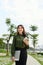 Pretty young woman carrying a cup of takeaway coffee and a file in an urban park as she gives the camera a dazzling smile