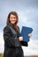 Pretty, young woman celebrating joyfully her graduation - spreading wide her arms, holding her diploma