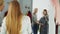 Pretty young woman is checking fashionable coat in fitting room with her friend helping her to appraise garment. They