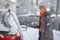 Pretty, young woman cleaning her car from snow after heavy snowstorm