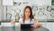 Pretty young woman with cup of tea using digital tablet on light cozy kitchen